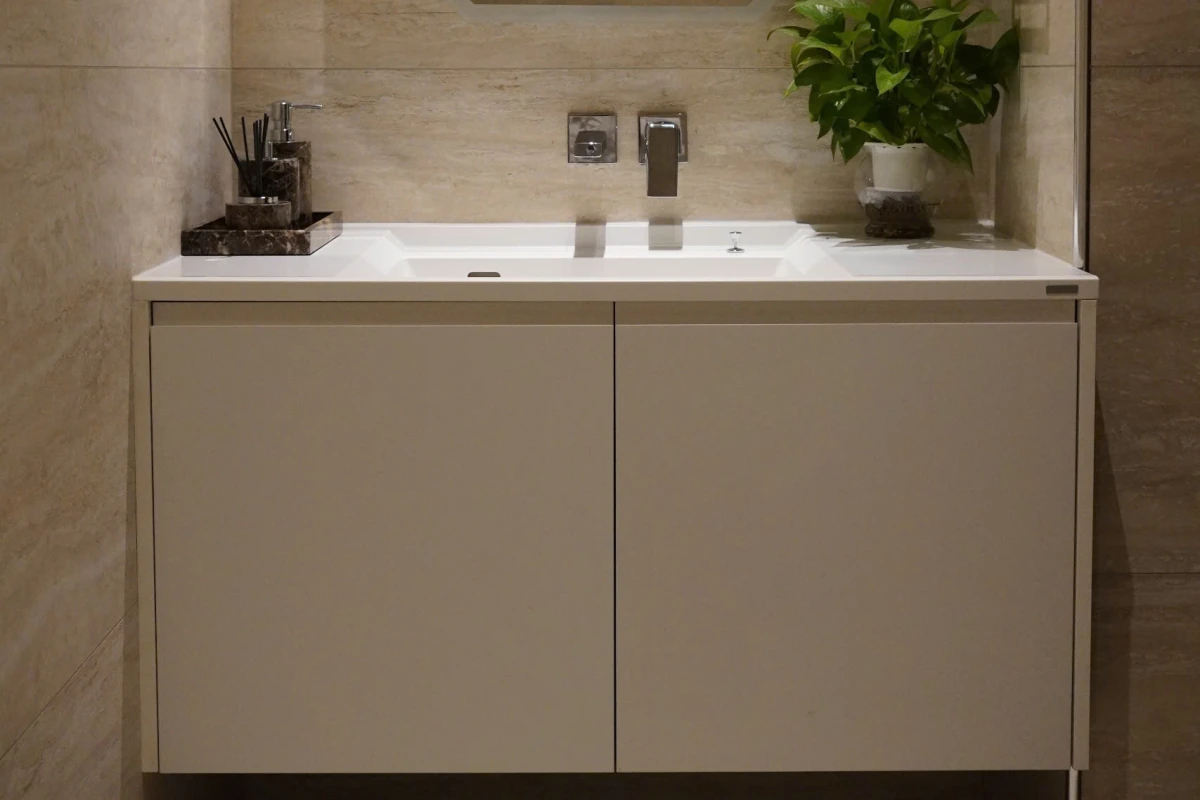 Lavabo liền khối SQ chậu giữa trên tủ trắng hai cánh, tường ốp đá màu be, phòng tắm biệt thự Hà Nam