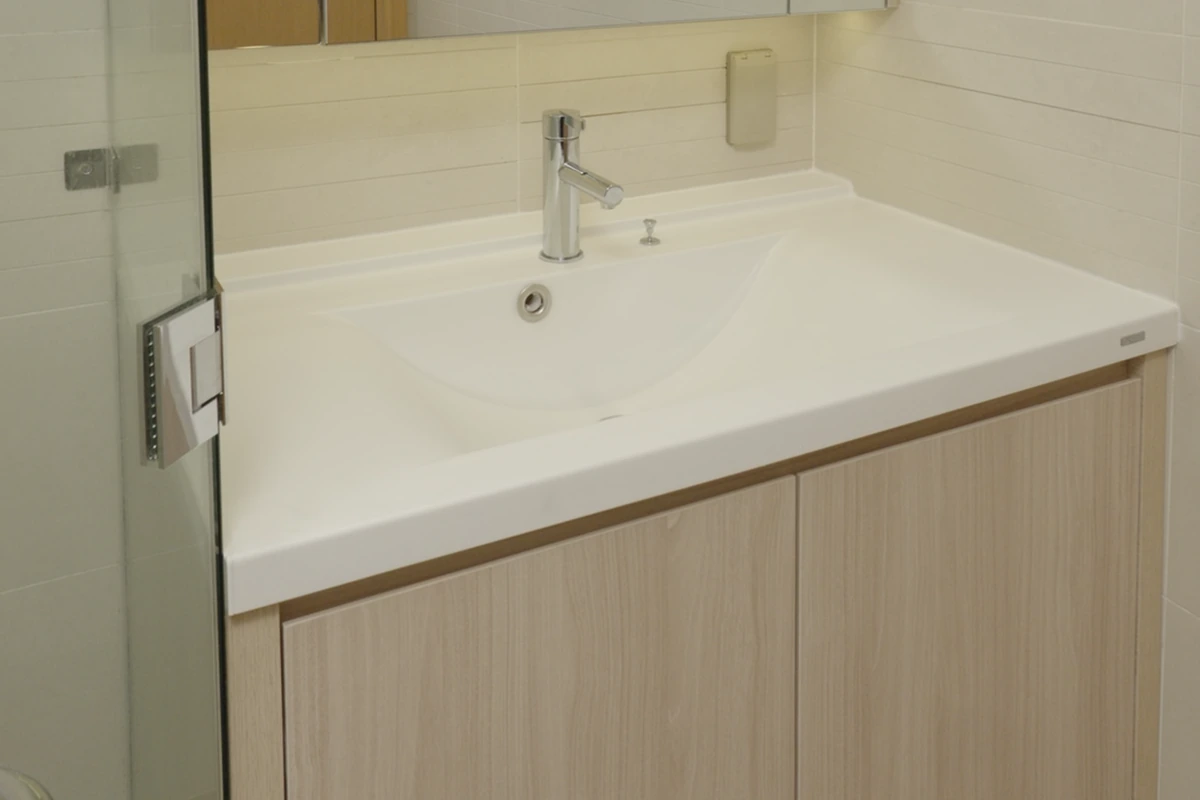 Lavabo liền khối TQ đặt chậu giữa trên tủ gỗ hai cánh, cạnh vách kính khu tắm đứng, phòng tắm chính căn hộ Sala
