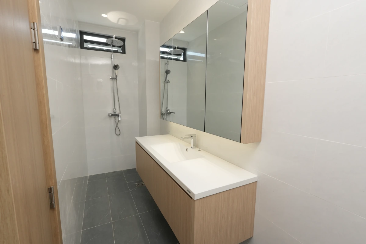 Toàn cảnh phòng tắm nhà phố Quận 7: khu tắm đứng, lavabo liền khối TQ trên tủ gỗ treo tường và tủ gương